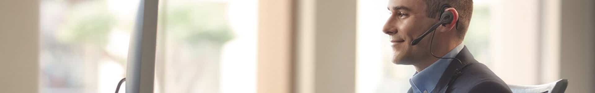 Man wearing headset working at a computer, focused and engaged in the task.