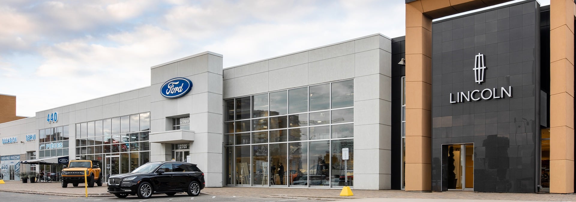 Exterior of a car dealership featuring Ford and Lincoln logos with parked vehicles.