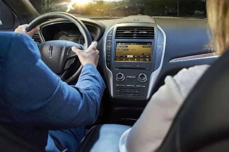 Driver using the SYNC® 4 touchscreen and voice control inside a Lincoln vehicle