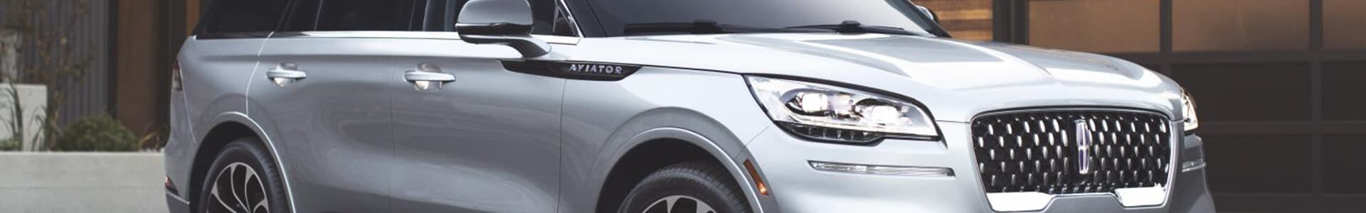 Silver Lincoln Aviator SUV parked, showcasing sleek design and front grille.