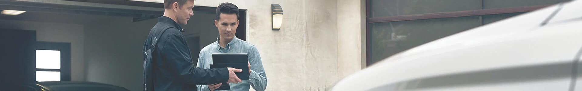 Driver inside a car using a digital dashboard and steering wheel in an urban setting.