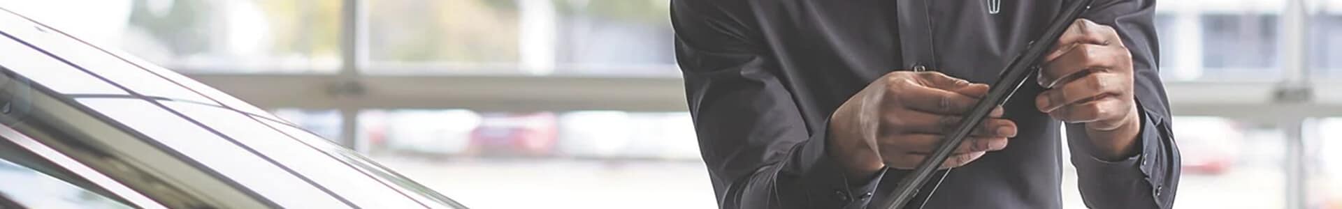 Person in dark attire checking a car windshield wiper in a garage setting.
