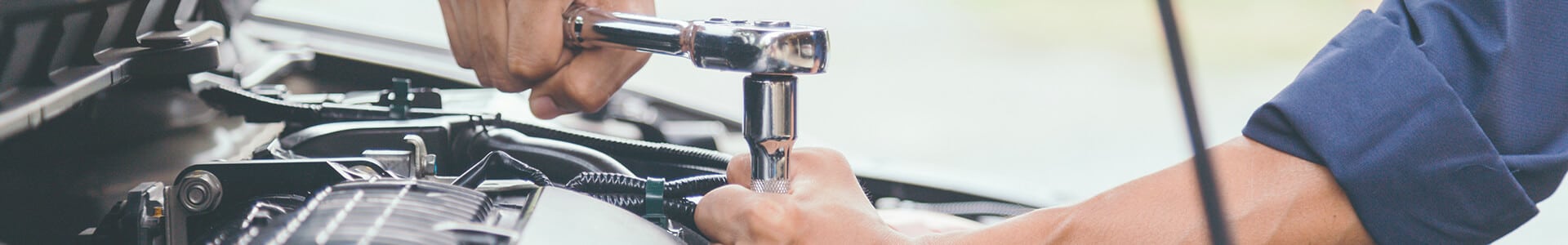 Mechanic using a wrench to fix car engine, close-up on hands and tool. Auto repair service.