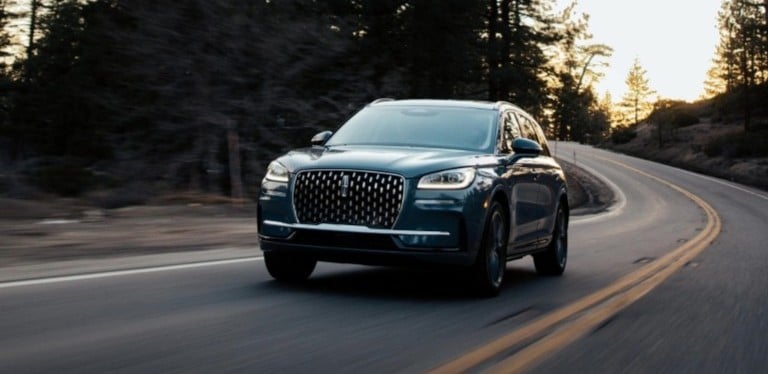 SUV driving on a winding forest road at sunset, emphasizing adventure and performance.